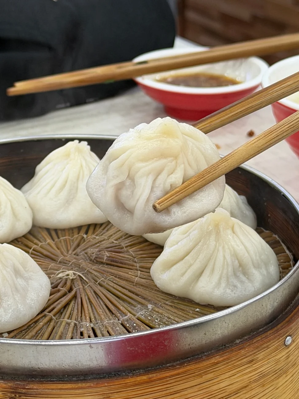 Xiaolongbao lifted with chopsticks above a steamer at Shanshan, Shanghai